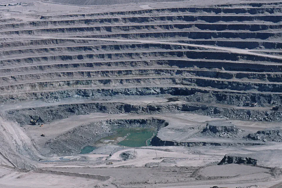 A large basin of mined rock with a pool of water in the center.